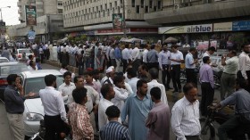 People stand outside of their office buildings following an earthquake tremor in Karachi April 16, 2013.