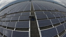 A photographer takes a picture of solar panels on the roof of the Palexpo Exhibition Center in Geneva, Switzerland, October 16, 2012. 