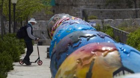 A man rides a scooter near giant globes displayed outside the walls of Jerusalem's Old City April 17, 2013. The globes exhibit, an initiative of the non-profit organization Cool Globes which aims to r