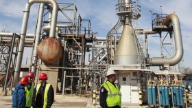 Refinery workers stand in front of the coker flare stack cooling tower after a press conference inside the LyondellBasell oil refinery in Houston, Texas March 6, 2013