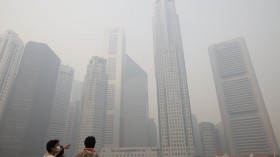 Tourists wearing face masks look at the hazy skyline of the Singapore business district June 20, 2013. 