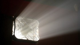 Beams of light pass through a fan mounted on a wall 