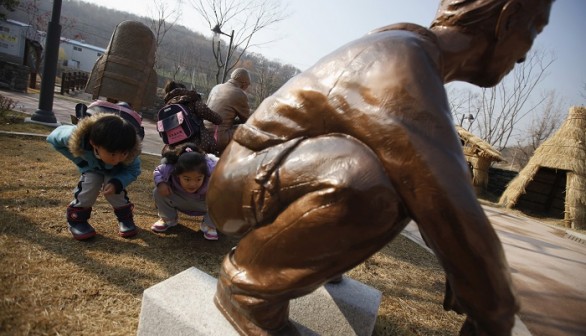 Children look at a statue of a man responding to the call of nature at the Toilet Culture Park in Suwon, about 46 km south of Seoul, November 22, 2012. 