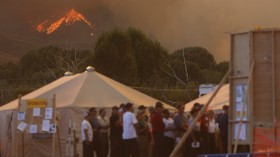 Flames from the Beaver Creek wildfire are visible in the background as fire crews attend a planning meeting outside Hailey, Idaho August 16, 2013