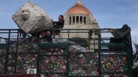 A volunteer hoists a bag filled with plastic bottles into a truck during an urban 