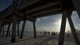 Surfers watch from the beach as waves generated by Tropical Storm Karen roll to the shore next to the Pensacola Beach Pier at Pensacola Beach, Fla.