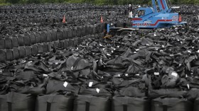 Workers move waste containing radiated soil, leaves and debris from the decontamination operation at a storage site in Naraha town, near the Fukushima nuclear campus 