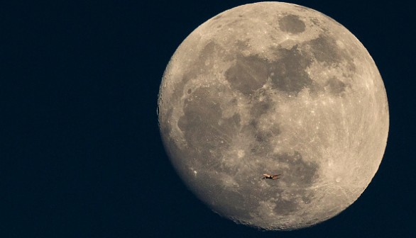 A Plane Is Dwarfed As It Flies Past The Moon