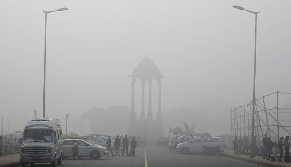 Vendors selling drinks stand beside vehicles near the India Gate war memorial on a smoggy day in New Delhi February 1, 2013.