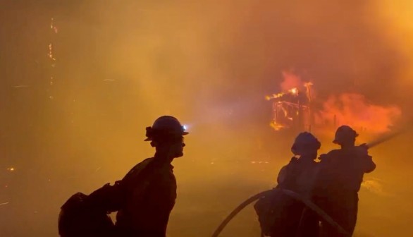 Firefighters direct water on a burning house during wildfires in San Bernardino, California