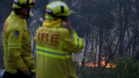 NSW Rural Fire Service and Fire and Rescue NSW personnel conduct property protection as a bushfire burns in Woodford NSW