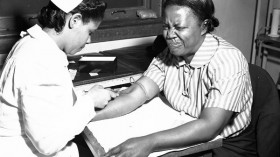 Pain -- A woman grimacing while having blood drawn