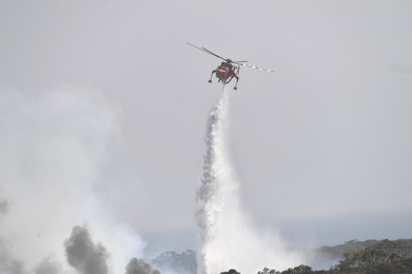 A helicopter drops water on bushfires that are sweeping through Stokes Bay on Kangaroo Island