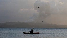 A fisherman paddles as the Taal Volcano continues to erupt in Talisay, Batangas