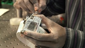 Stanford graduate student George Korir holds a programmable microfluidics kit built on music box parts. 