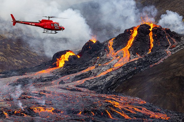 A helicopter flies close to the volcanic eruption