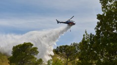 An helicopter drops its load of water to extinguish a fire