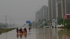 Rescue workers help people cross a flooded street after heavy rain that flooded the city of Zhengzhou