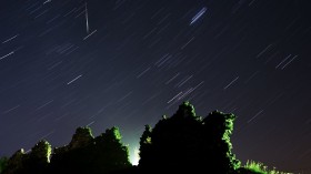 Perseid meteor crossing the night sky and stars trails