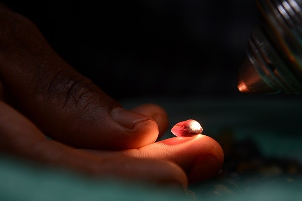 Sri Lankan gem dealer uses a torch to examine precious stones for flaws in Ratnapura district