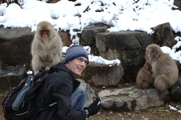 Visitor poses for a picture with Macaque monkeys 