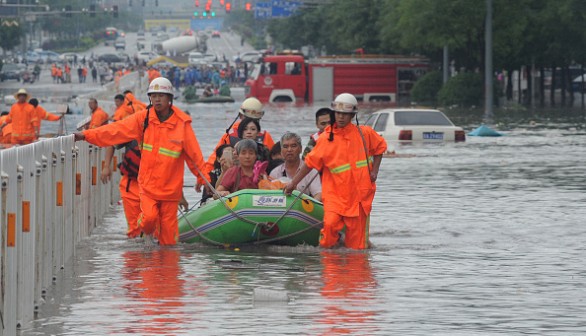 Fire workers transfer citizens with inflatable boat on flooded street 