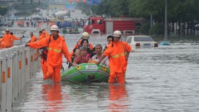 Fire workers transfer citizens with inflatable boat on flooded street 