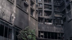 The exterior walls of a residential building stands charred in the wake of a fire 