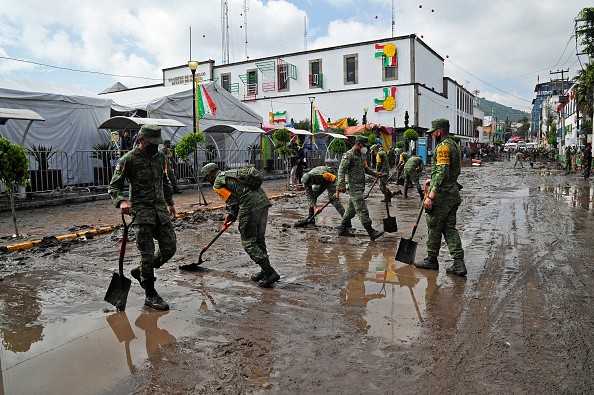 Members of the Mexican Army remove mud off the street after heavy rains that caused a flood 