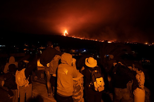 Tourists watch as lava flows from the Cumbre Vieja Volcano