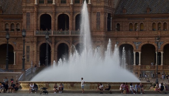 People gather around a water fountain amid a heatwave