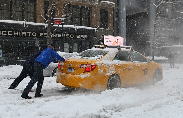  People push a taxi cab stuck on snow covered street during a winter storm 