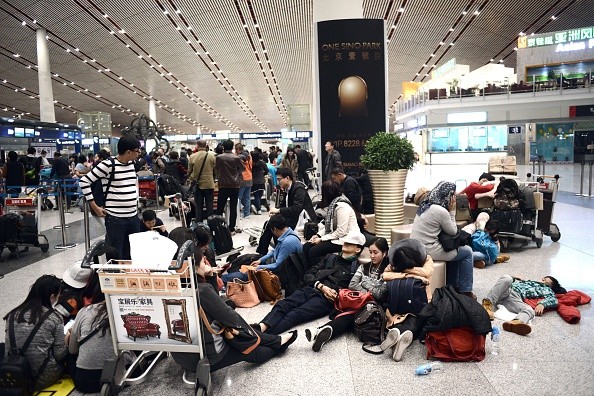 Passengers rest as they wait for their flights at the Beijing Capital International airport after heavy snowstorm cancelled and delayed numerous flights in Beijing