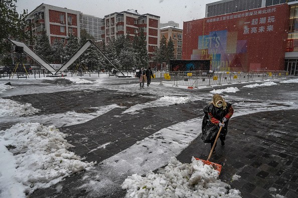 Worker shovels snow from in front of a shopping mall following a snowfall