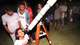 Young stargazer looks through a telescope as others queue for a view of the Leonids meteor shower 