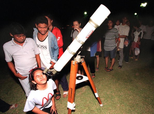 Young stargazer looks through a telescope as others queue for a view of the Leonids meteor shower 