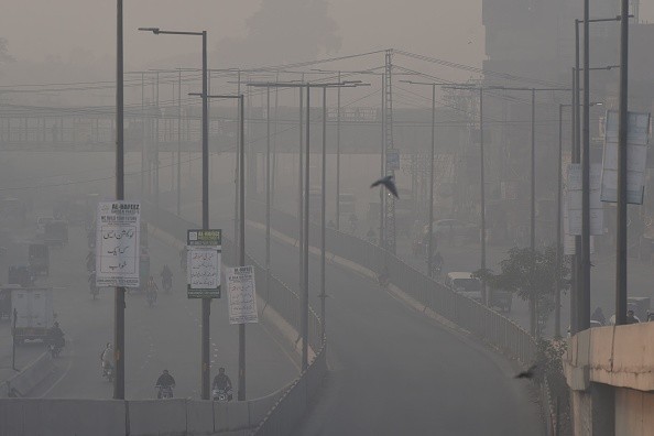 Commuters ride along a road amid smoggy conditions in Lahore 