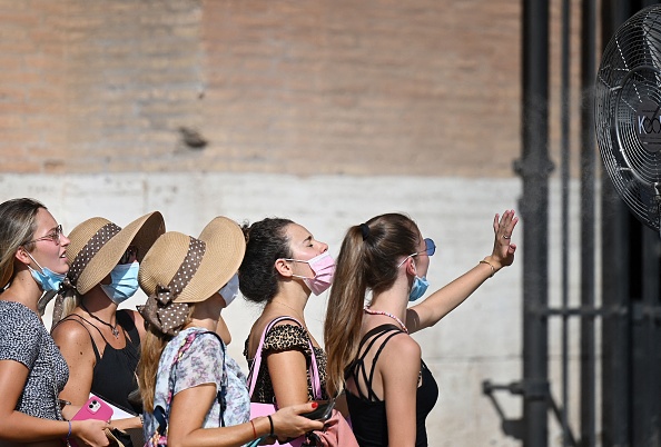 A group of women cool off in front of a cooling fan during a heatwave