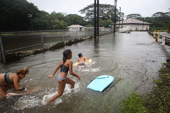 Residents playing in floodwaters at a baseball field during flooding 