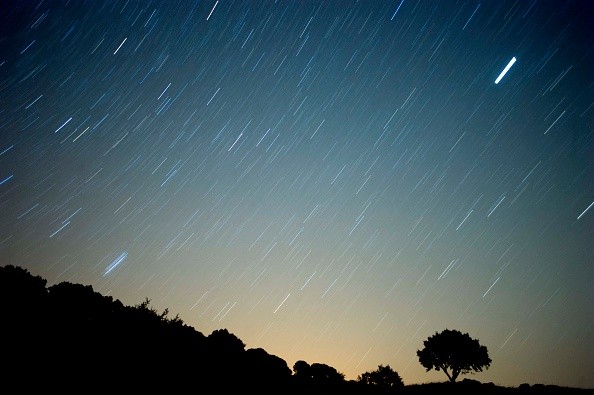 Meteor streaks across the sky against a field of stars during a meteorite shower 