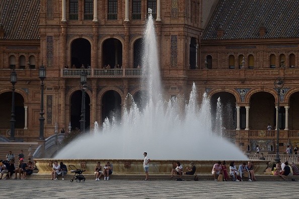 People gather around a water fountain amid a heatwave