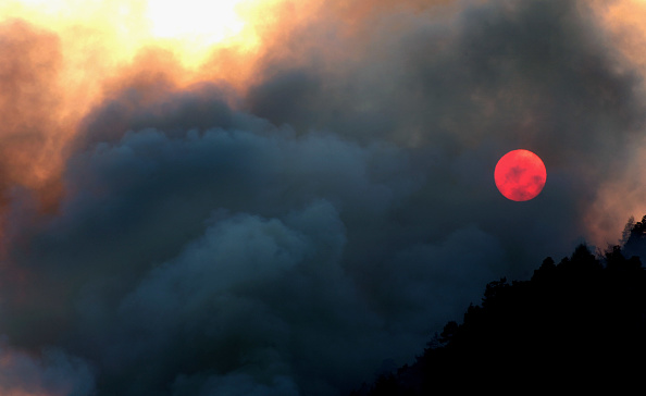 The sun dimmed by dense fog during a mountain forest fire 