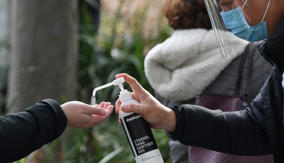 A health worker offers hand sanitiser outside a Covid-19 vaccination centre 