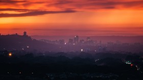 Red and purple sunset over hazy city