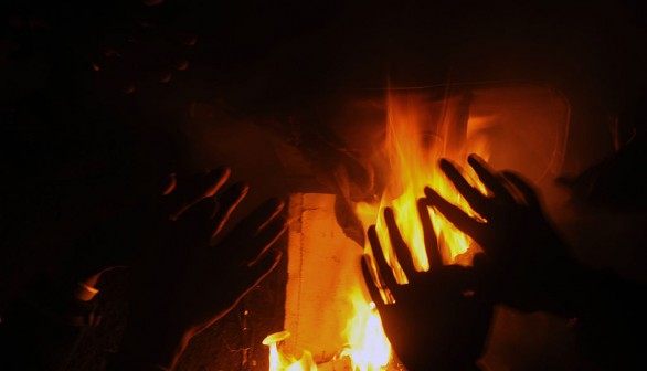 Indian people warm themselves near a bonfire