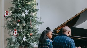 A Father and Her Child Playing a Piano Near a Christmas Tree