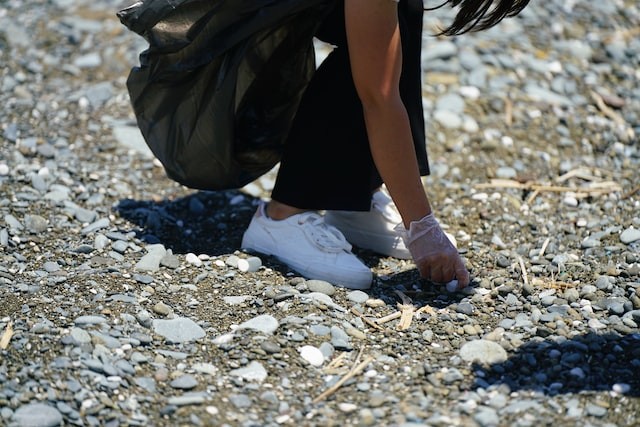 woman's hand collects garbage on the beach with gloves