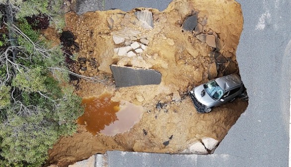 This aerial view shows two cars siting in a large sinkhole that opened during a day of relentless rain