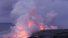 Hill burned near ocean under white sky