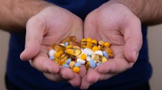 A pile of multi-colored pills in a male hand
